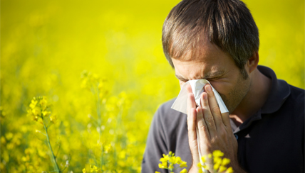 man in a field blowing his nose