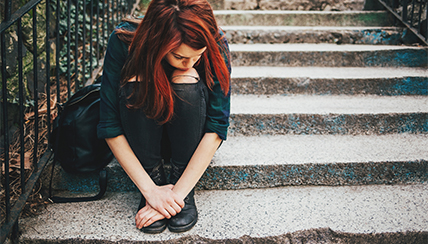 Sad girl sitting on a stoop looking at her shoes