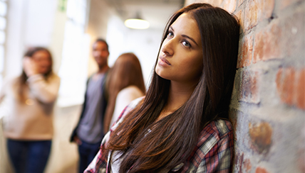 Depressed girl looking into the distance with a group of kids behind her