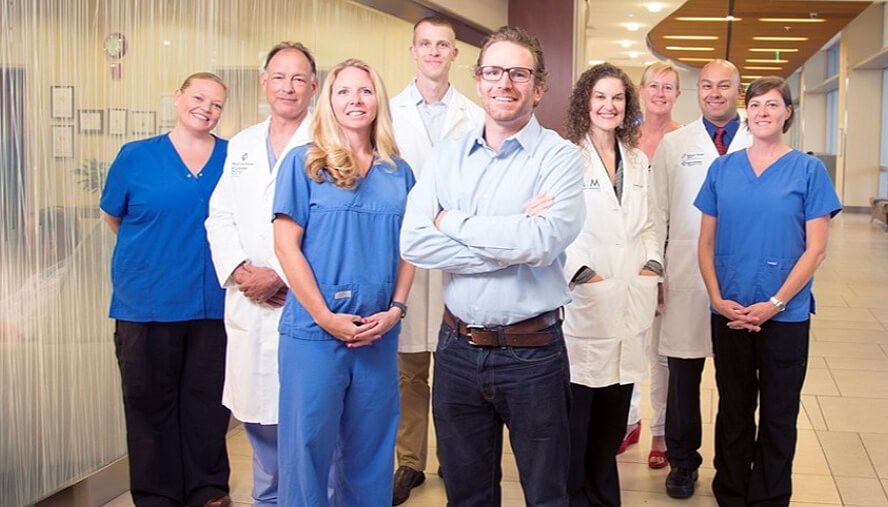 A healthy Eric White stands in the middle of care team members Cara Mlodzik, RN; Kevin Miller, MD; Misty Sieracki, RN; Tristan Huie, MD; Stephanie Wilson, MD; Kathy Owens, RN, BSN; Ken Lyn-Kew, MD; and Theresa Bone, RN, BSN. A healthy Eric White stands in the middle of care team members Cara Mlodzik, RN; Kevin Miller, MD; Misty Sieracki, RN; Tristan Huie, MD; Stephanie Wilson, MD; Kathy Owens, RN, BSN; Ken Lyn-Kew, MD; and Theresa Bone, RN, BSN.