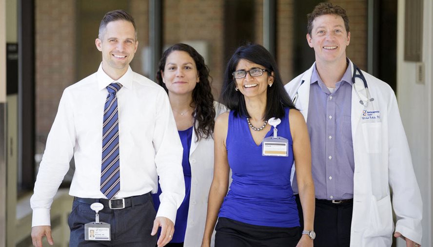 Four doctors walking towards the camera smiling