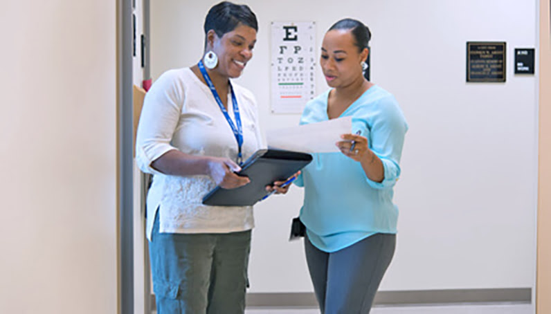 Two doctors looking at a chart standing in a hallway