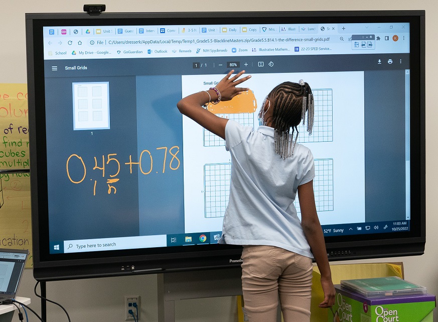 young girl using a touch screen for math exercises