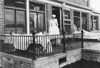 Nurse taking morning temperature of outdoor sleepers, 1905.