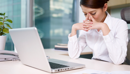 Woman in front of laptop, experiencing stress