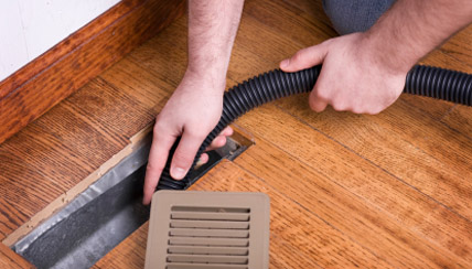 person vacuuming in air vent