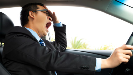 man yawning sleepily while driving