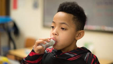 Boy taking a breath off an inhaler