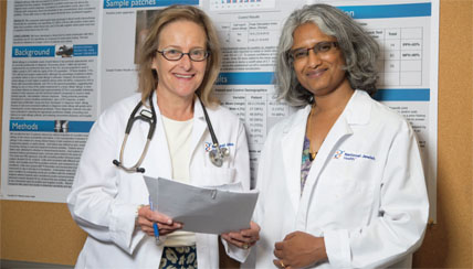 Two female physicians standing with paperwork