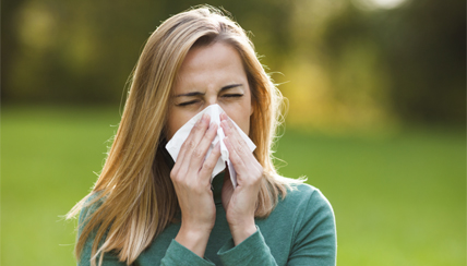 woman sneezing into a tissue