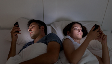 couple looking at mobile phones in bed