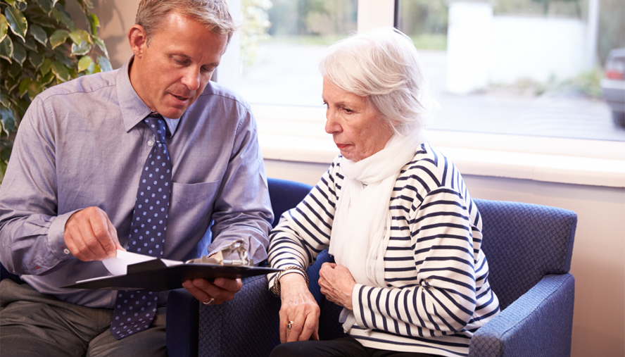 Doctor reviewing paperwork with elderly female patient.