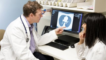 Two researchers looking at a CAT scan on a computer and talking about it