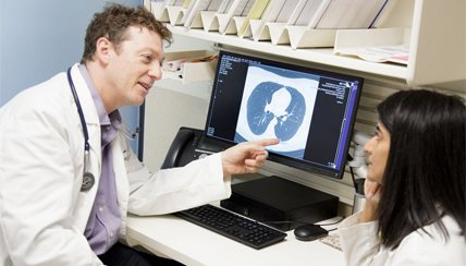 Doctors looking at a CAT scan on a computer