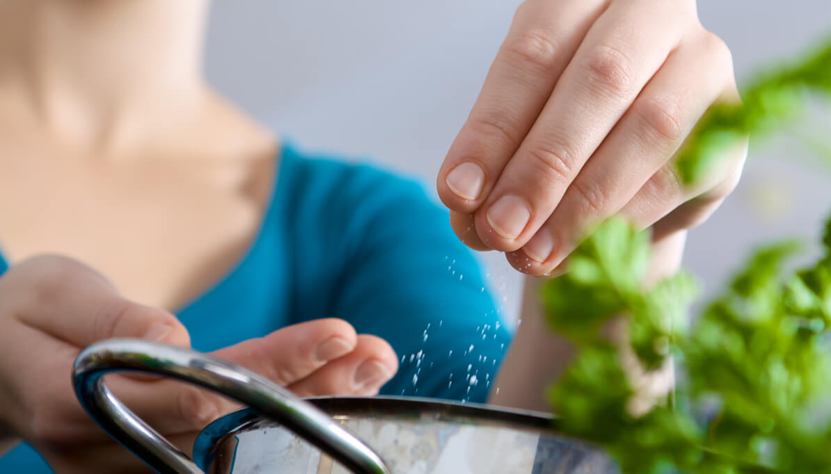 sprinkling salt on a plate of food