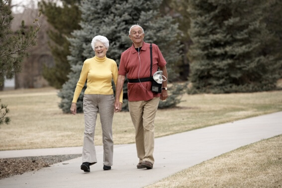 Couple walking in the park with a portable oxygen concentrator