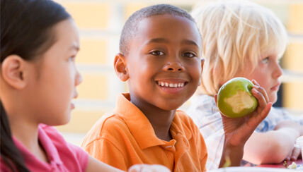 boy eating an apple and smiling