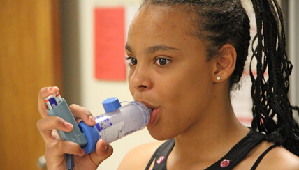 Child using asthma spacer and inhaler